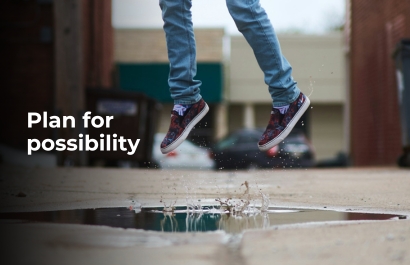 Feet jumping off the ground on top of a puddle of water.